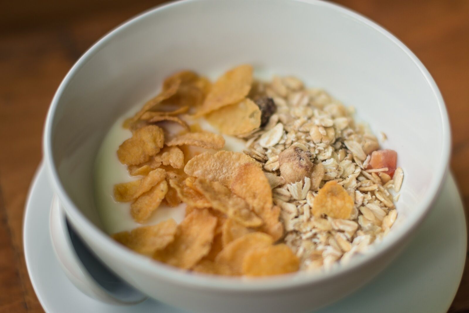 Un tazón de cereal con leche y hojuelas.
