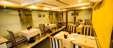 A restaurant with multiple tables and chairs, each set with plates, cutlery, and napkins.