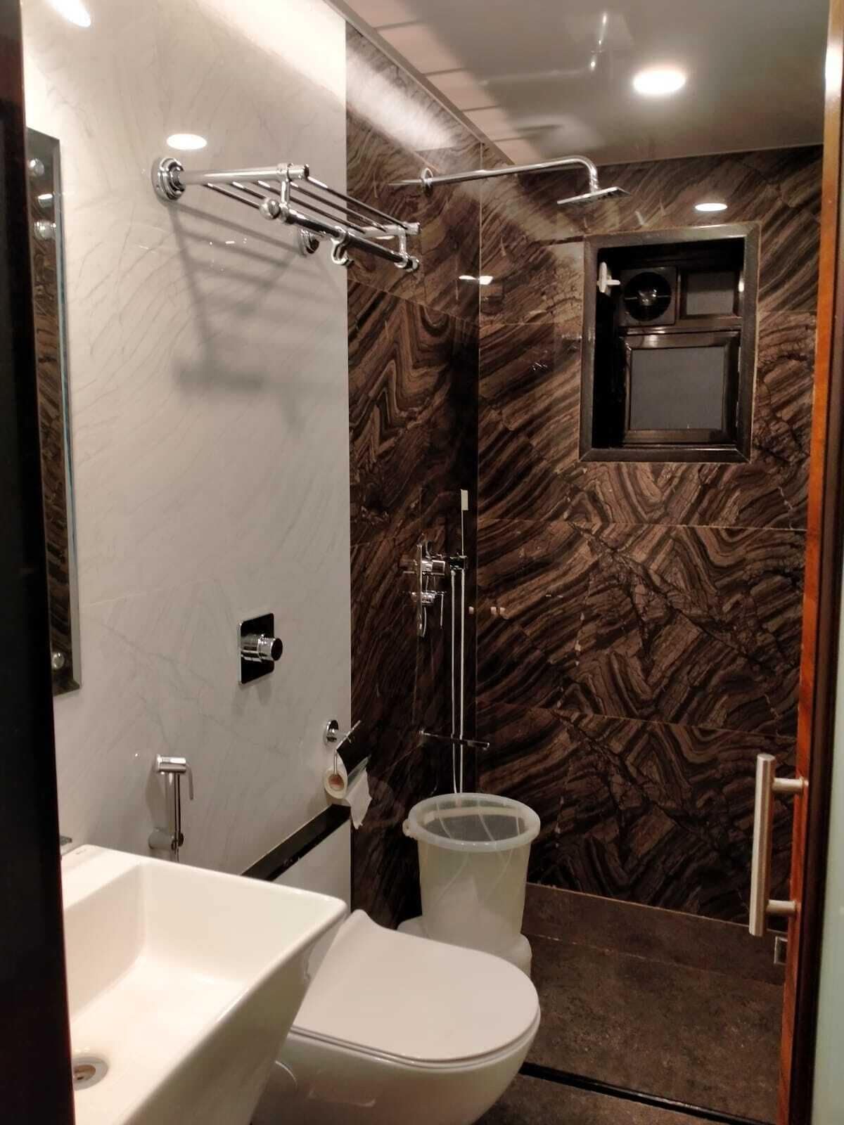 A modern bathroom with a marble wall, a shower with a glass enclosure, and a toilet.