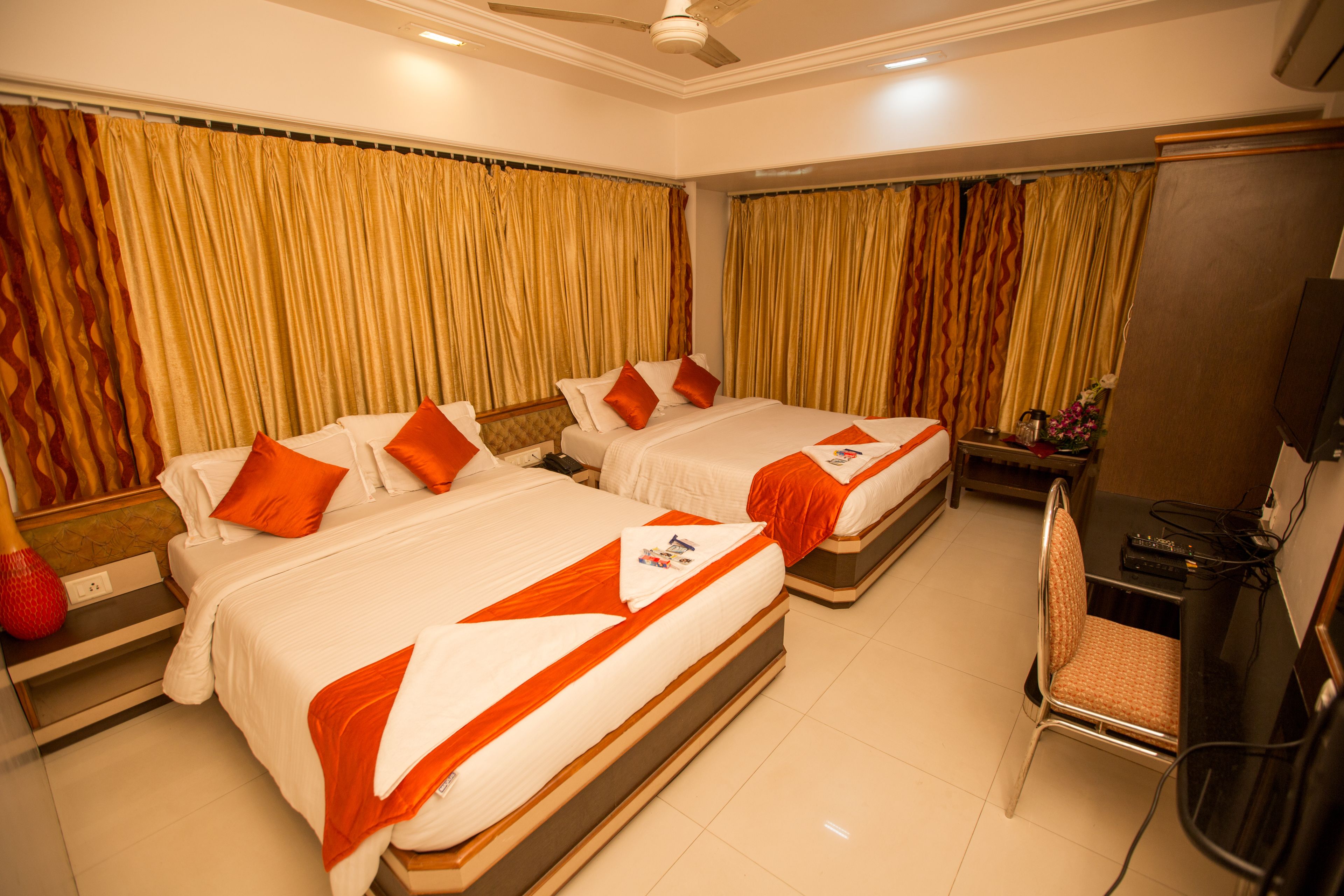 A hotel room with two beds, a desk, and a chair.