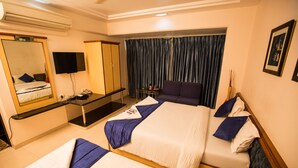Une chambre d’hôtel avec deux lits, un bureau, une armoire, une télévision et une fenêtre avec des rideaux.
