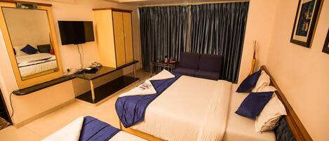 Une chambre d’hôtel avec deux lits, un bureau, une armoire, une télévision et une fenêtre avec des rideaux.