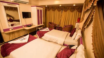 Habitación de hotel con dos camas, un tocador con espejo, un televisor y un escritorio con silla.