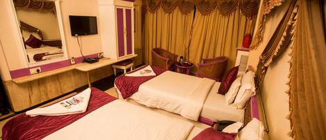 A hotel room with two beds, a vanity with a mirror, a television, and a desk with a chair.