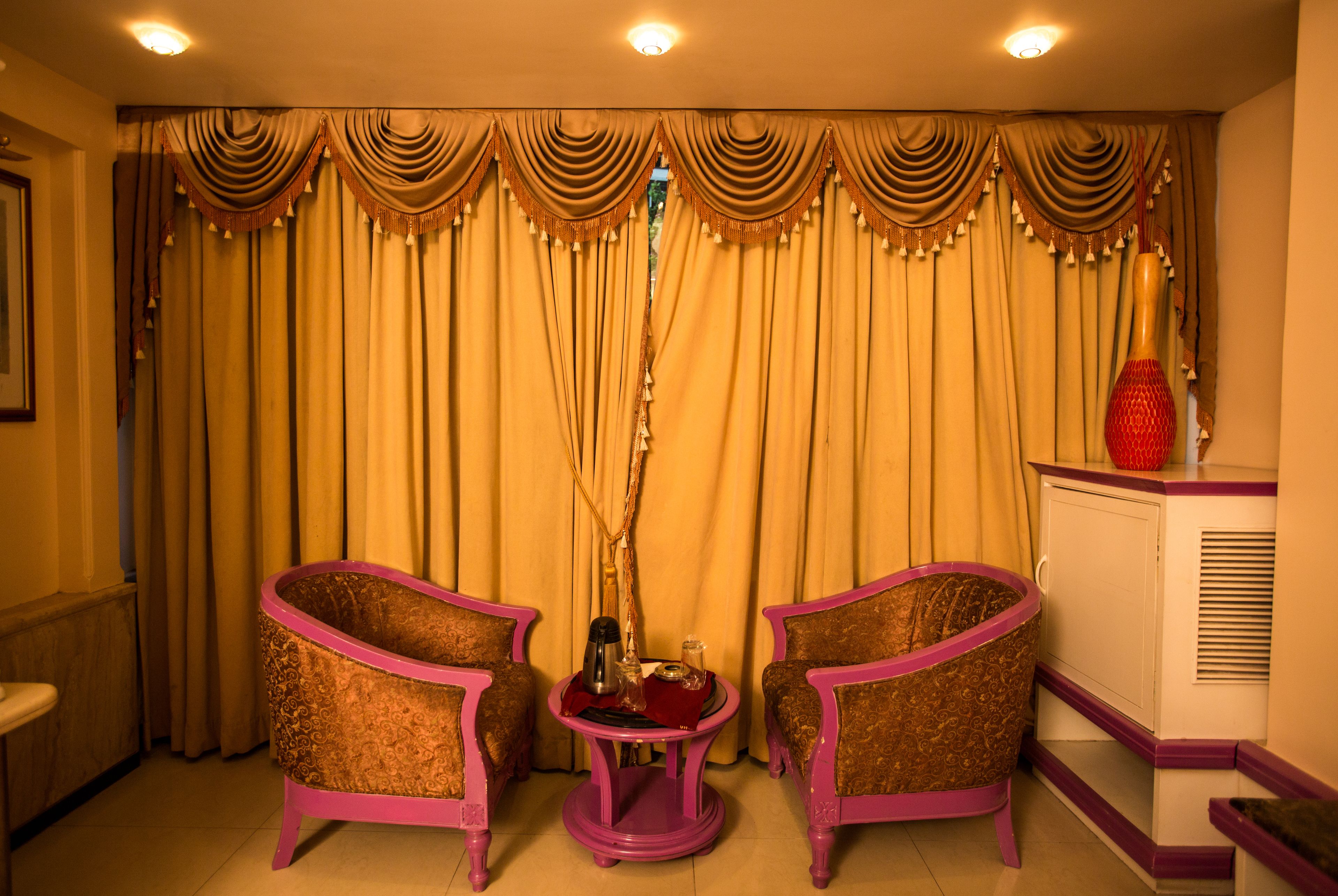Una habitación con dos sillones, una mesita redonda y un aparador.