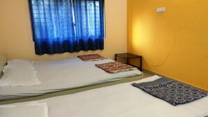 Una habitació amb dos llits, una taula petita i una cortina.