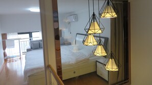 A hotel room with a bed, bedside tables, a mirror, and a hanging light fixture. - Yunzu Aparthotel - Huanlegu Branch (Shanghai)