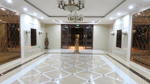 A spacious lobby with a geometric tile floor, a grand chandelier, and a glass elevator entrance. - Yunzu Aparthotel - Huanlegu Branch (Shanghai)