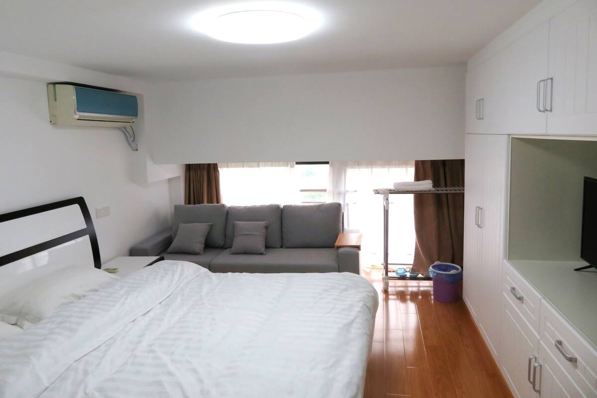 A hotel room with a bed, a sofa, a television, and a wardrobe.