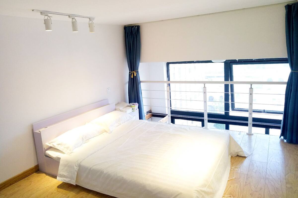 A bedroom with a bed, a window with curtains, and a ceiling light fixture.
