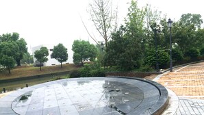 A circular water feature with a tiled edge, surrounded by a brick pathway and greenery. - Yunzu Aparthotel - Huanlegu Branch (Shanghai)
