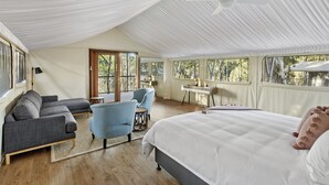 A spacious room with a large bed, a sofa, and a chair. There is a desk and a window with a view of trees. - Sanctuary By Sirromet (Mount Cotton)