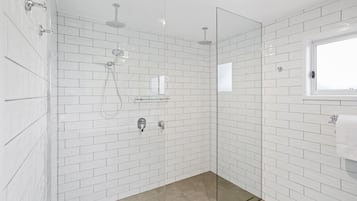 A modern bathroom with white subway tiles, a glass shower enclosure, and a window providing natural light.