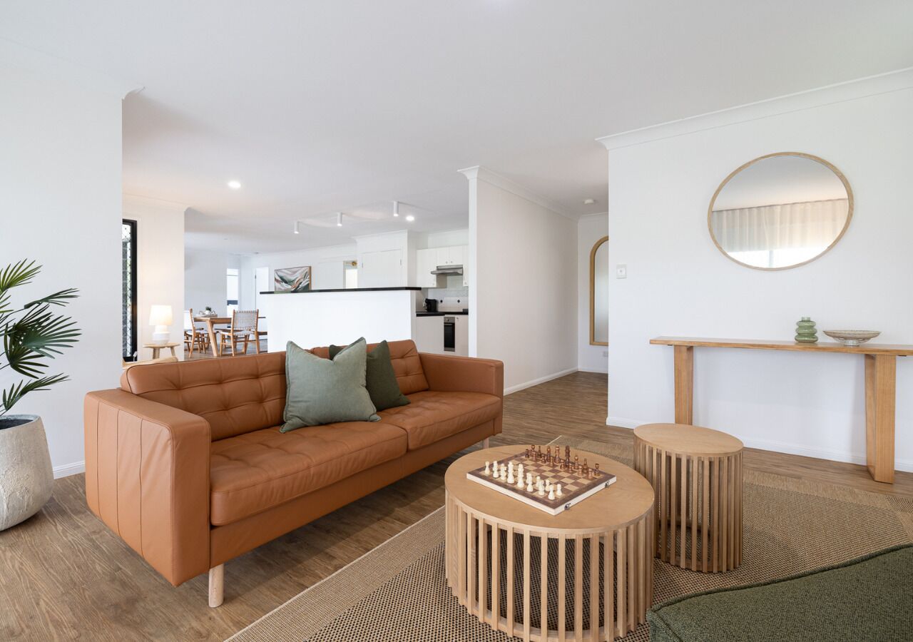 A modern living room with a sofa, coffee table, and a round mirror on the wall.