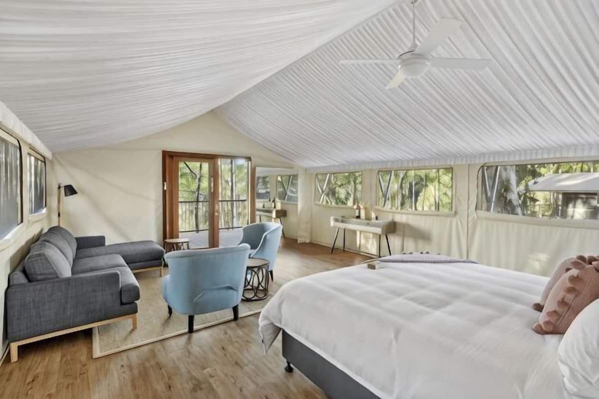 A spacious room with a bed, a sofa, a chair, and a desk.