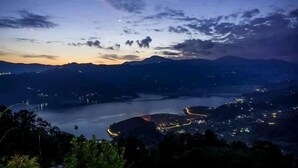 Vista nocturna d'un paisatge de muntanyes amb un riu i una població.