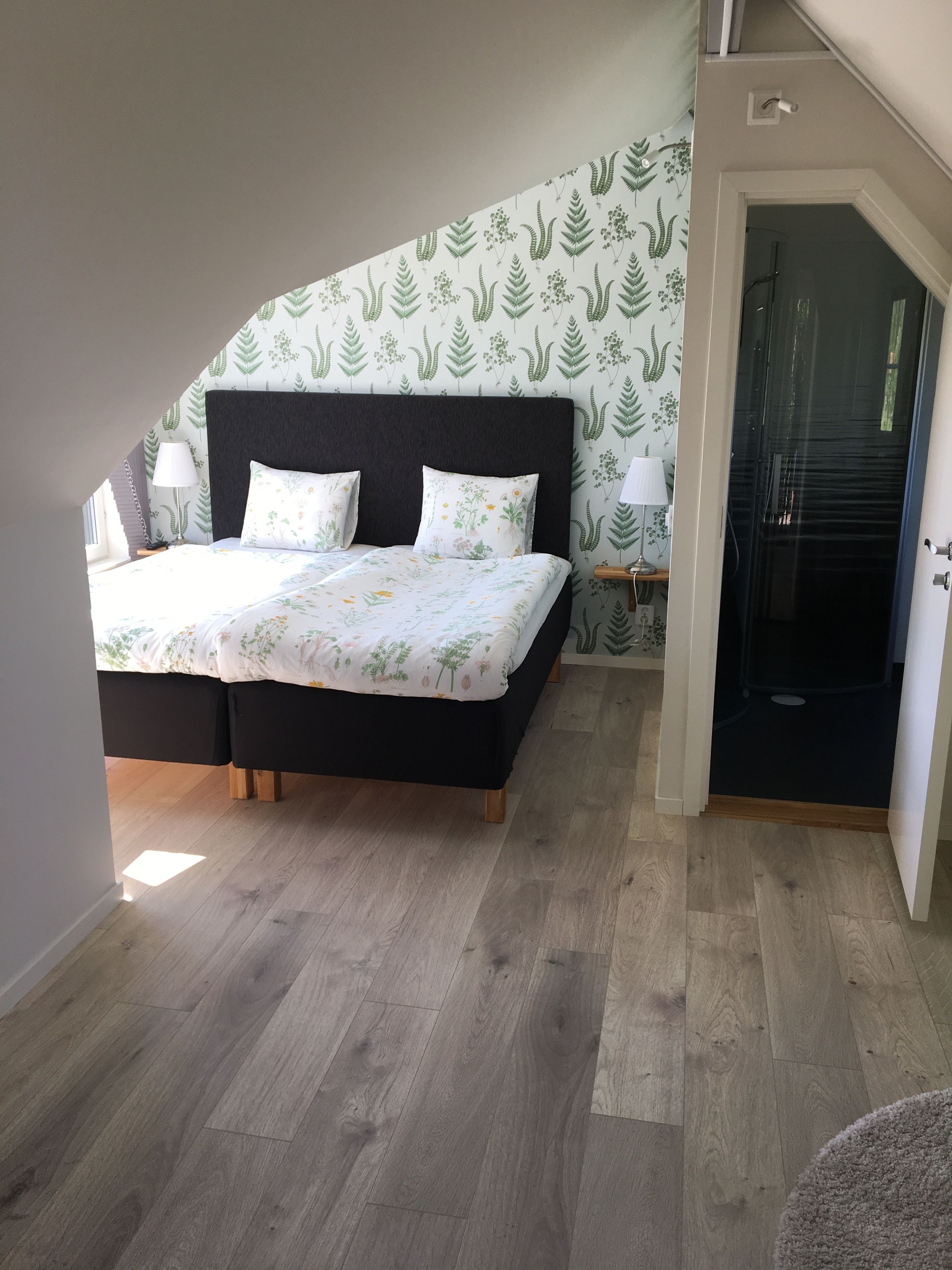 Ein Schlafzimmer mit einem Bett, zwei Nachttischlampen, einem Holzboden und einer Wand mit Muster.
