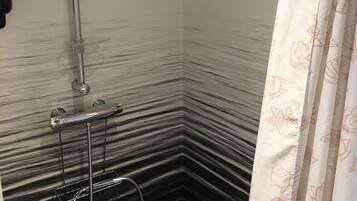 Une salle de bain équipée d’une douche, d’un porte-serviettes et d’un ventilateur fixé au mur.
