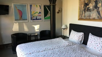 Una habitación de hotel con una cama grande, dos sillas, una mesita y un cuadro en la pared.