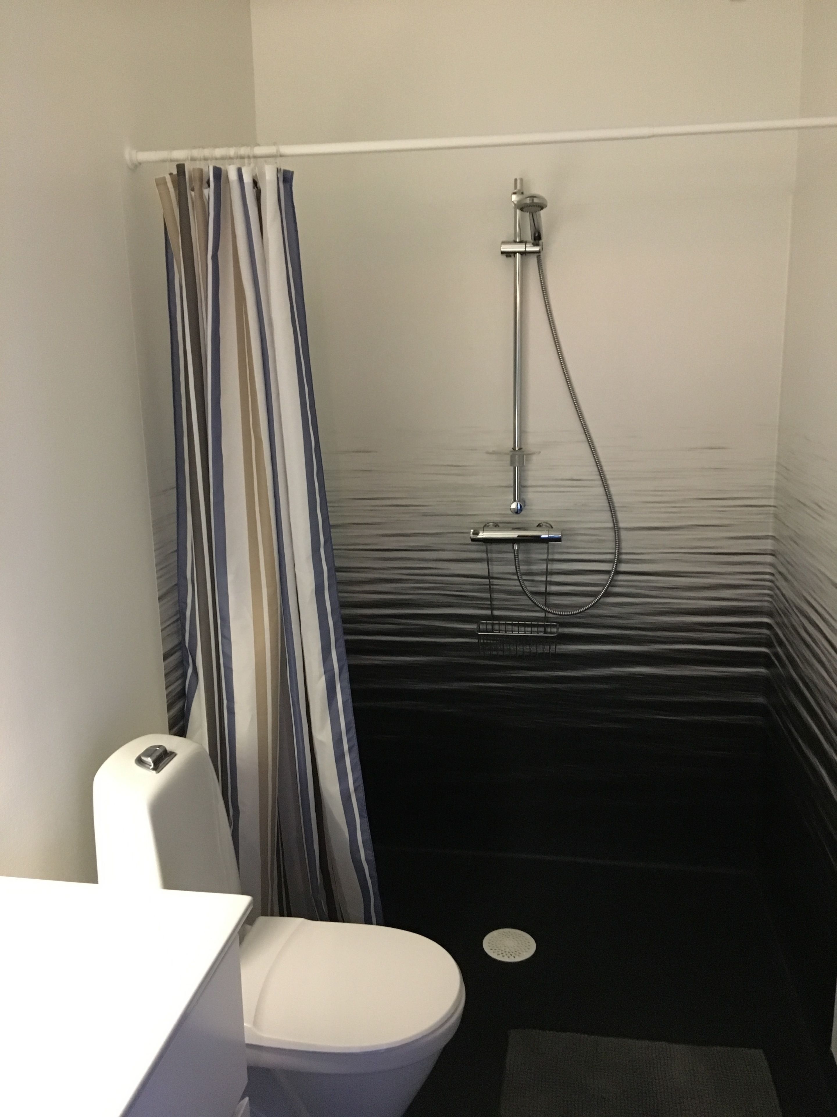 Un baño pequeño y moderno con ducha, inodoro y cortina de baño a rayas.