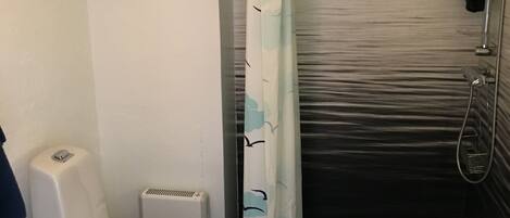 A bathroom with a toilet, a shower, and a sink.