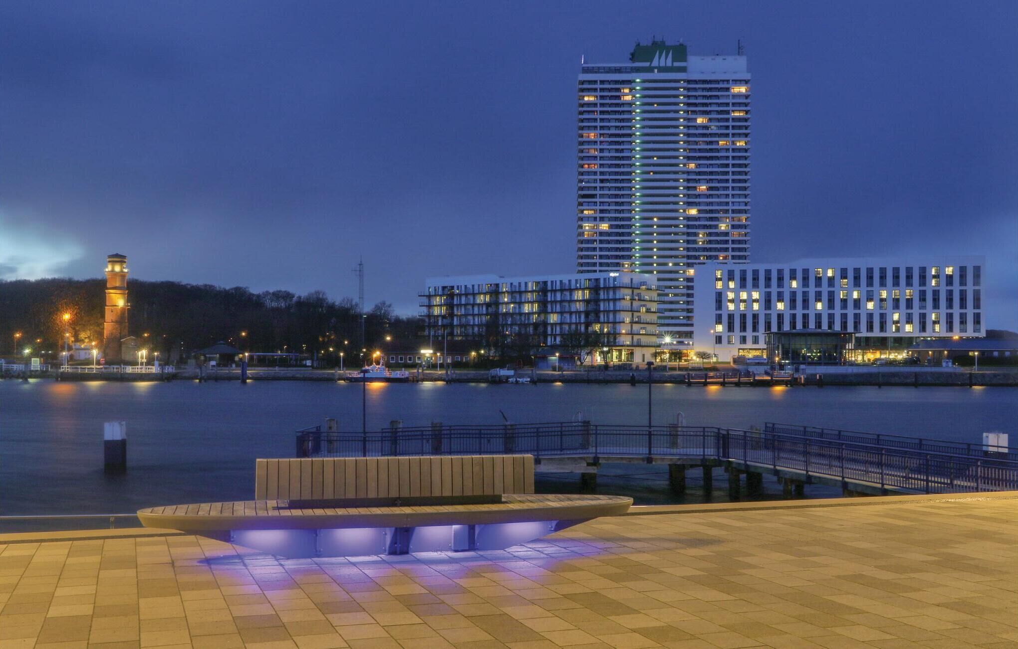 A waterfront hotel with a modern design, featuring a prominent tower and multiple high-rise buildings in the background.