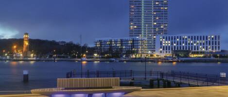 A waterfront hotel with a modern design, featuring a prominent tower and multiple high-rise buildings in the background.