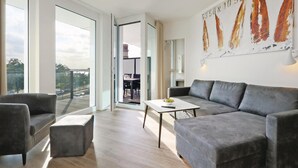 Una sala de estar moderna con sofás grises, una mesa de centro y un ventanal grande.