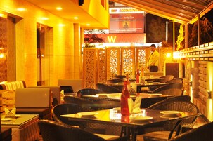 Um restaurante em ambiente interno com móveis de vime, um menu visível e uma pessoa atrás do balcão.