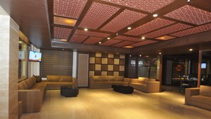 Um hall amplo com design moderno, apresentando um sofá modular, uma mesa de centro e uma parede decorativa com padrão geométrico.
