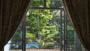 Ein Zimmer mit einer großen Glasdoor zu einem Balkon mit Pool und üppiger Bepflanzung.