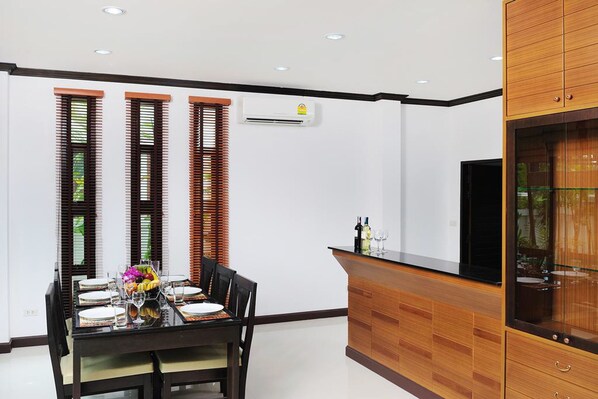 Una cocina moderna con comedor, que incluye un armario de madera, encimera negra y una mesa de comedor con platos, vasos y frutero.