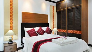 Een hotelkamer met een groot bed, een houten hoofdeinde en een kledingkast met verstelbare lamellen.