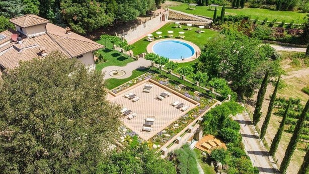 Un resort con piscina, tumbonas y un jardín cuidado.