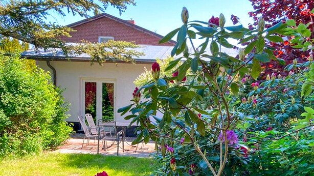 Une maison dotée d’un patio, d’une pelouse et de diverses plantes et fleurs.