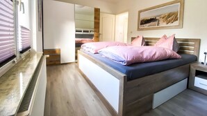 Une chambre à coucher avec un lit, une armoire, un miroir et un tableau accroché au mur.
