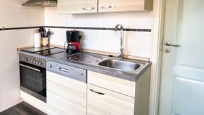 Une cuisine compacte équipée d’une cuisinière, d’un four, d’un lave-vaisselle et d’une machine à café.