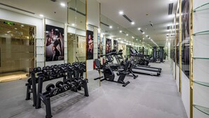 Un gimnasio moderno con paredes espejadas, diversos equipos de ejercicio y un ambiente limpio y bien iluminado.