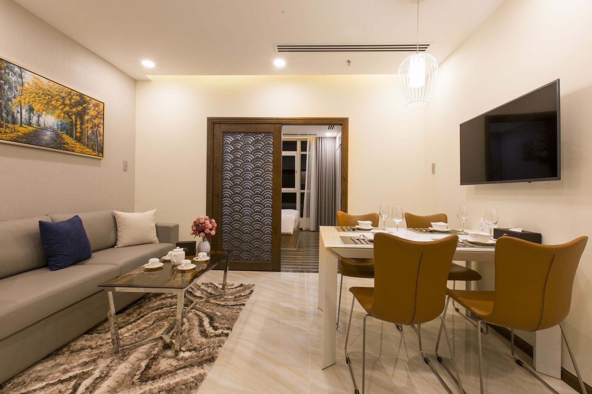 Un salón moderno con sofá, mesa de centro y comedor con sillas y una mesa dispuesta para dos.