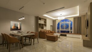 Una sala de estar moderna con comedor, un conjunto de sofás y un amplio ventanal con detalles decorativos.