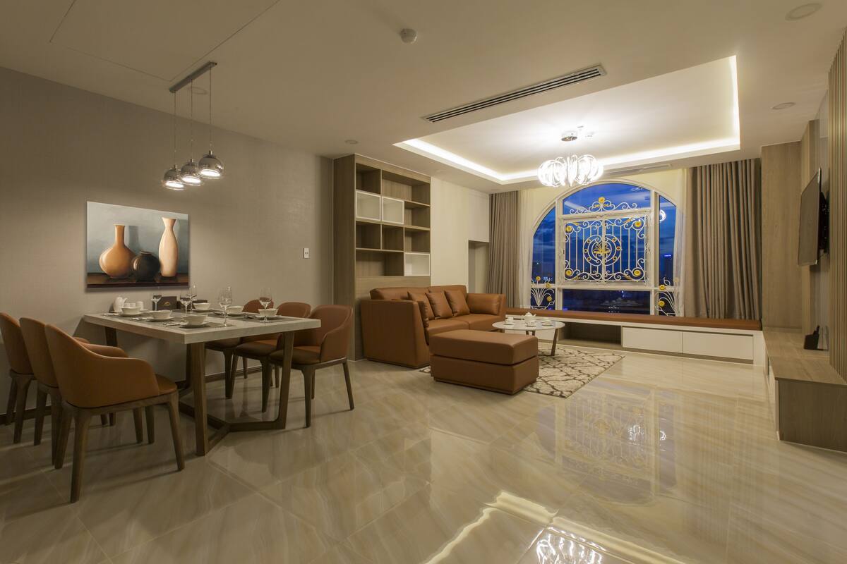 A modern living room with a dining area, a sofa set, and a large window with decorative glass.
