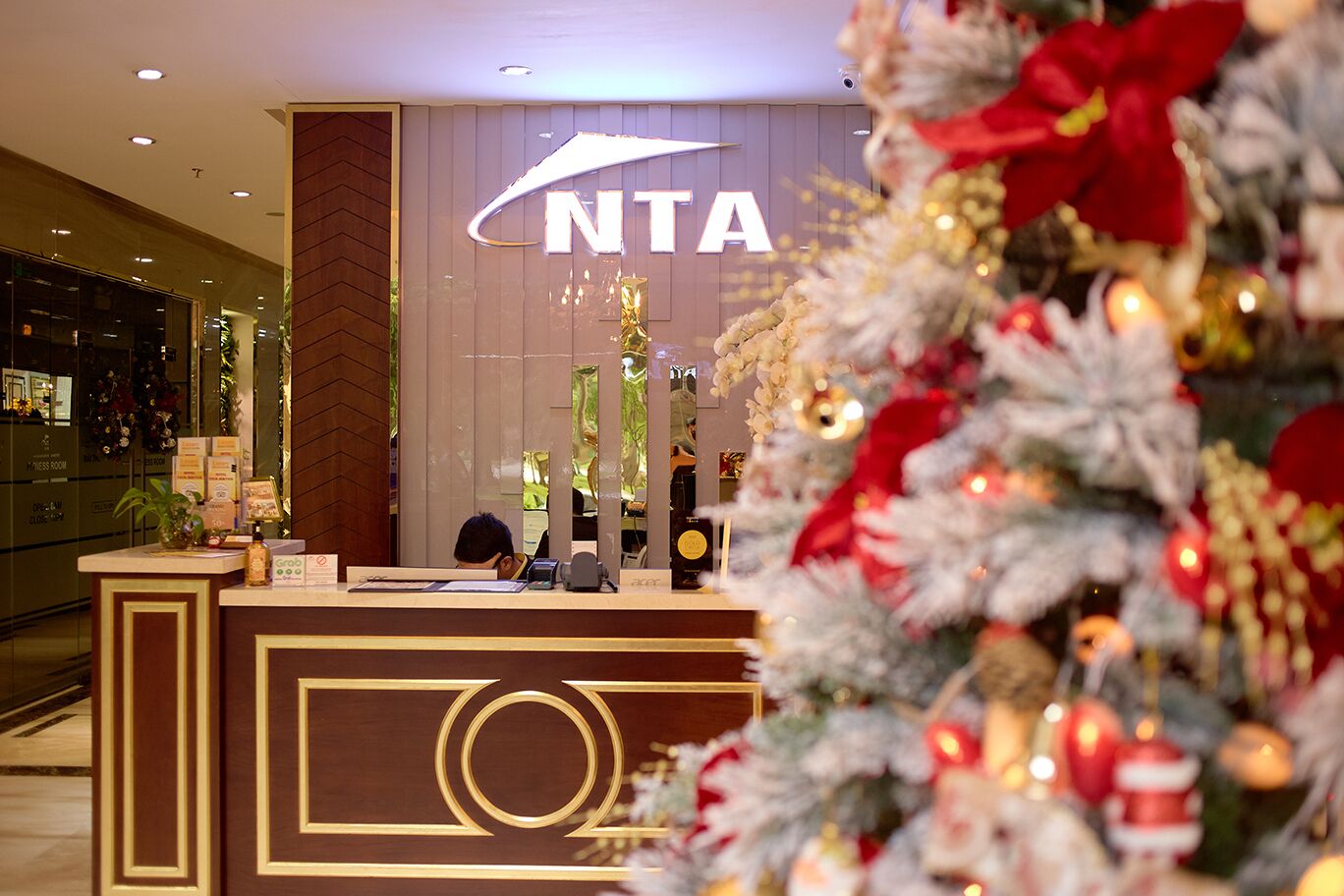 A hotel reception desk with a 'NTA' sign, a Christmas tree, and a bar area in the background.