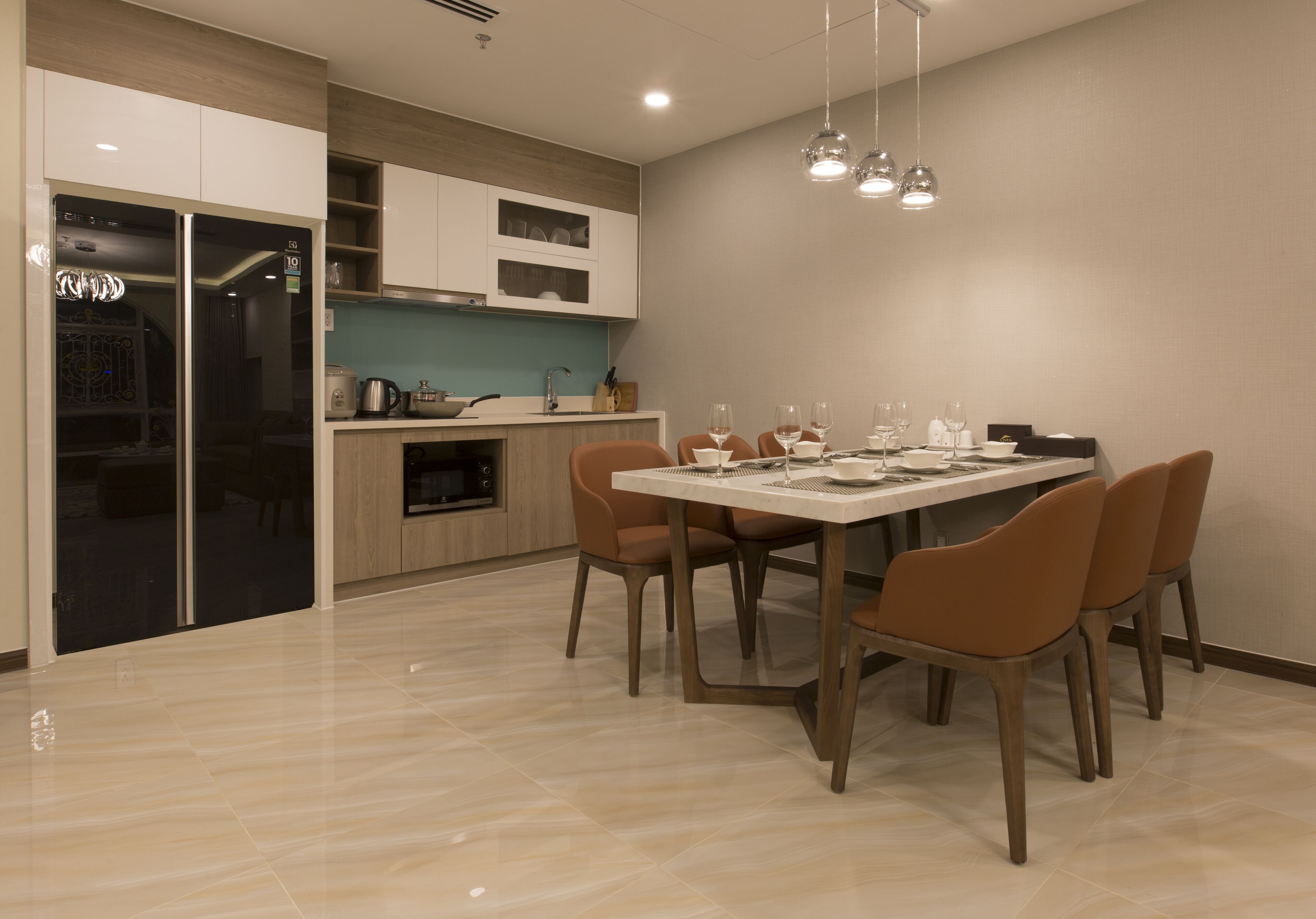 A modern kitchen with a dining area. It includes a kitchen island, a refrigerator, and a dining table with chairs.
