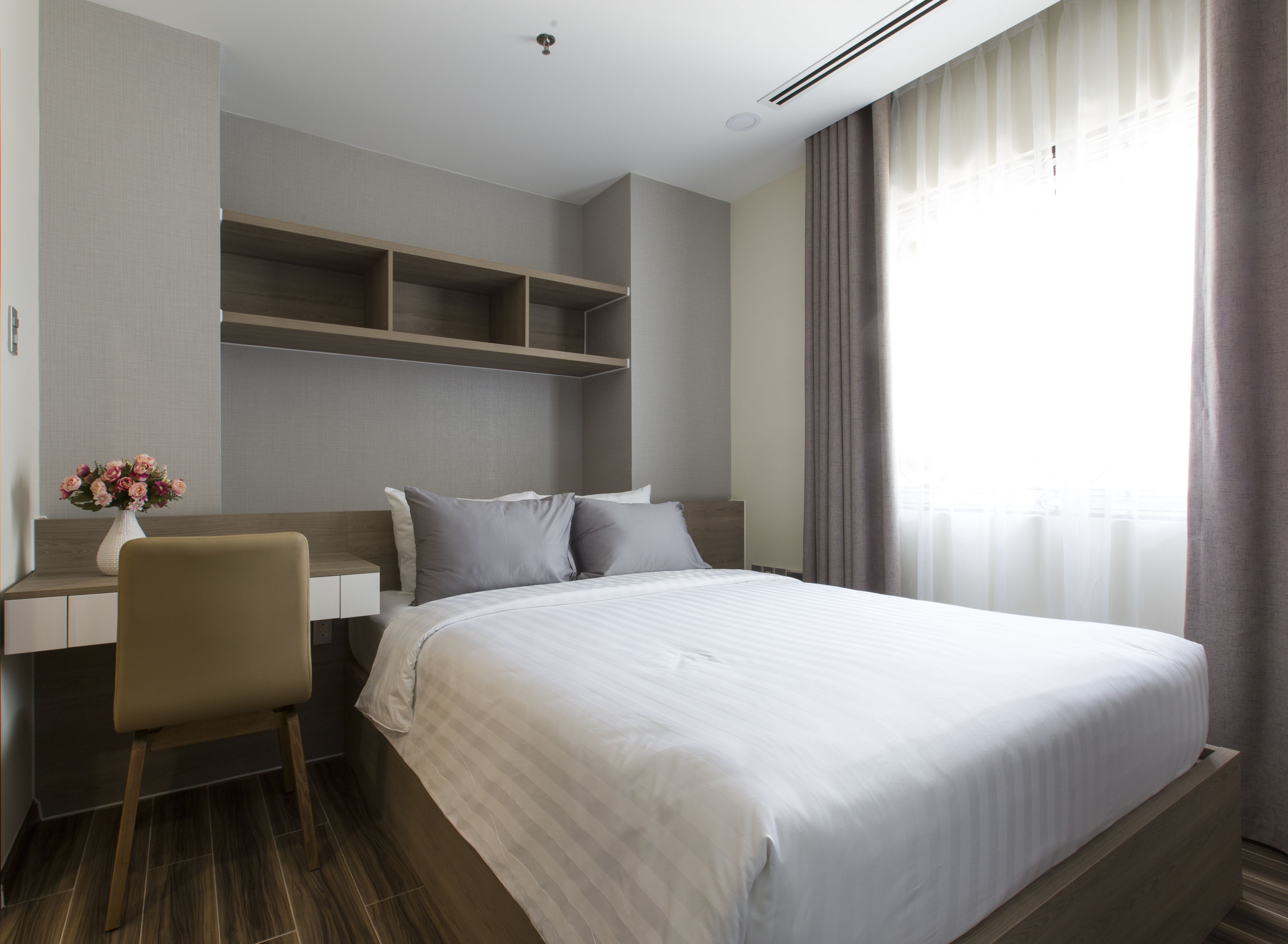Ein modernes Hotelzimmer mit einem großen Bett, einem Schreibtisch mit Stuhl und einem fensterbepflanzten Fenster.