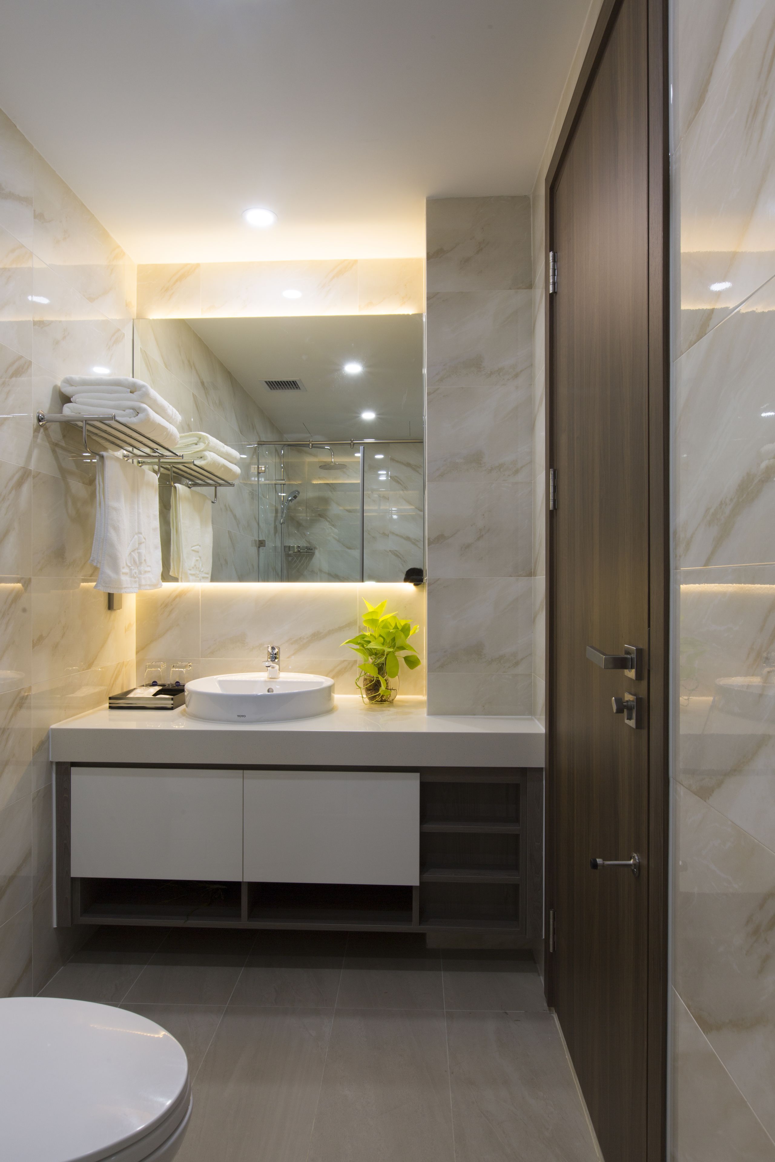 A modern bathroom with a marble vanity, a sink, a mirror, and a toilet.