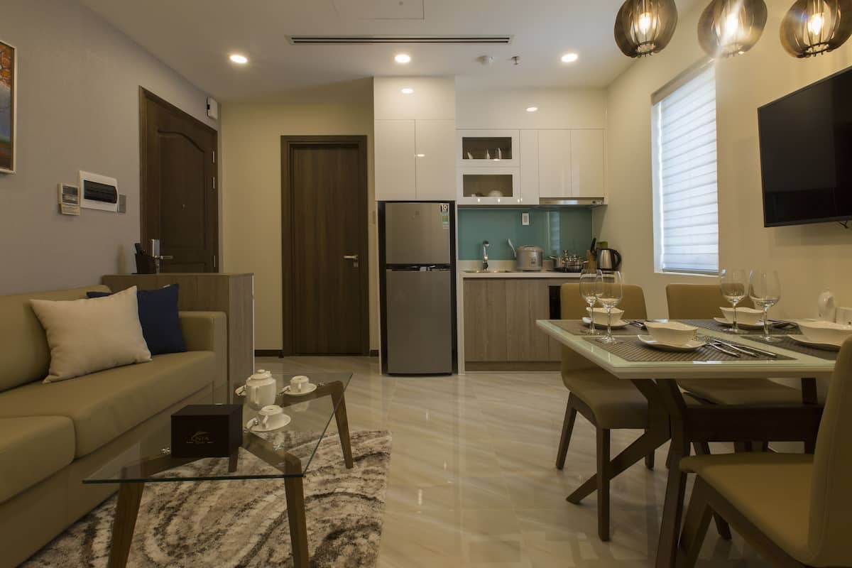 A modern kitchen with a refrigerator, stove, and dining area with chairs and a table set for a meal.