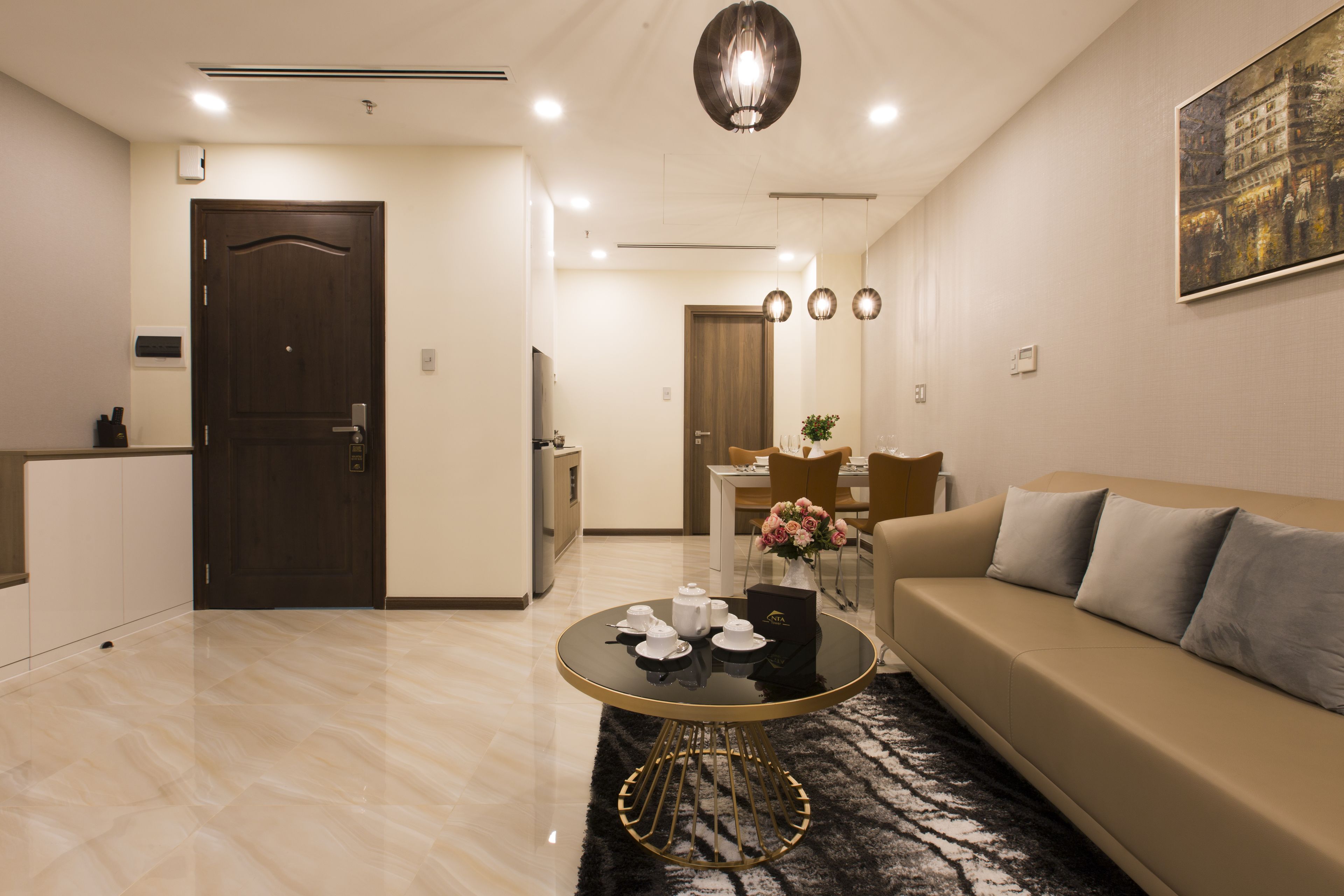 A modern living room with a sofa, a round coffee table, and a dining area in the background.