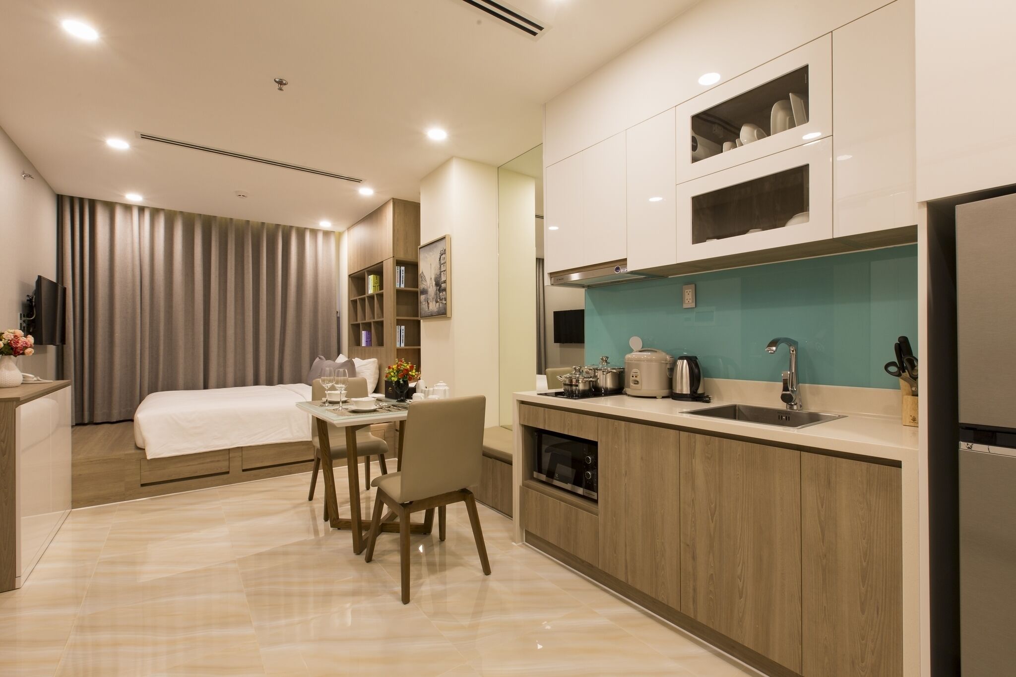 Une chambre d’hôtel moderne dotée d’un coin repas, d’une kitchenette et d’un lit.
