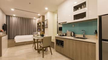 A modern hotel room with a dining area, kitchenette, and a bed.