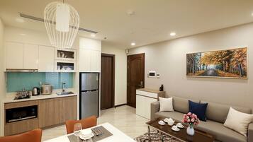 Un apartamento moderno con cocina, comedor y sala de estar. Cuenta con refrigerador, microondas y mesa de comedor con sillas.